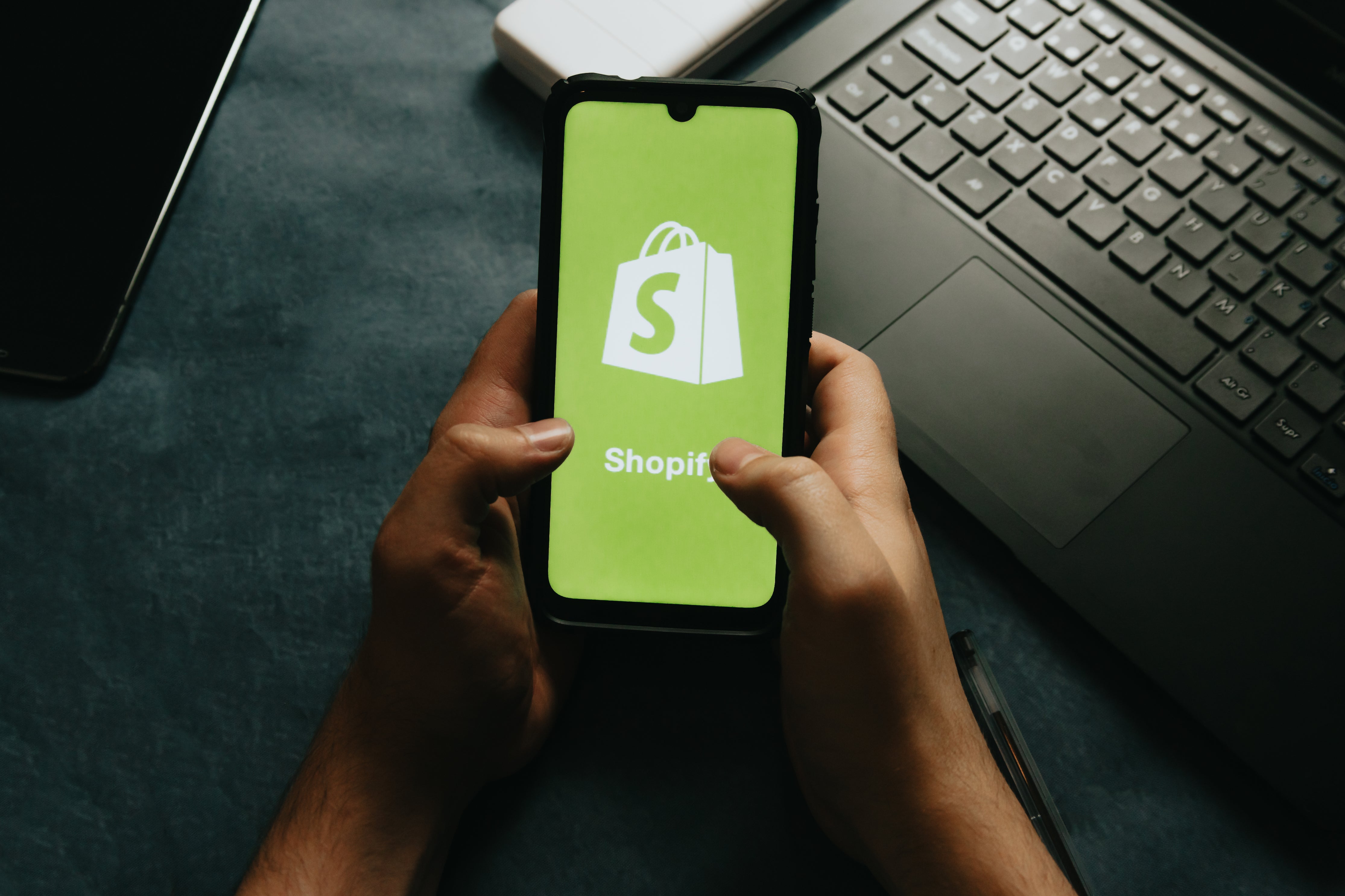 hands-holds-a-cell-phone-showing-the-shopify-logo
